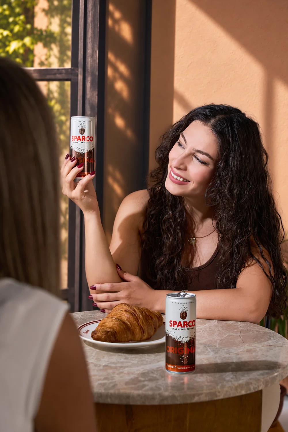 A woman sharing Sparco with a friend at a café